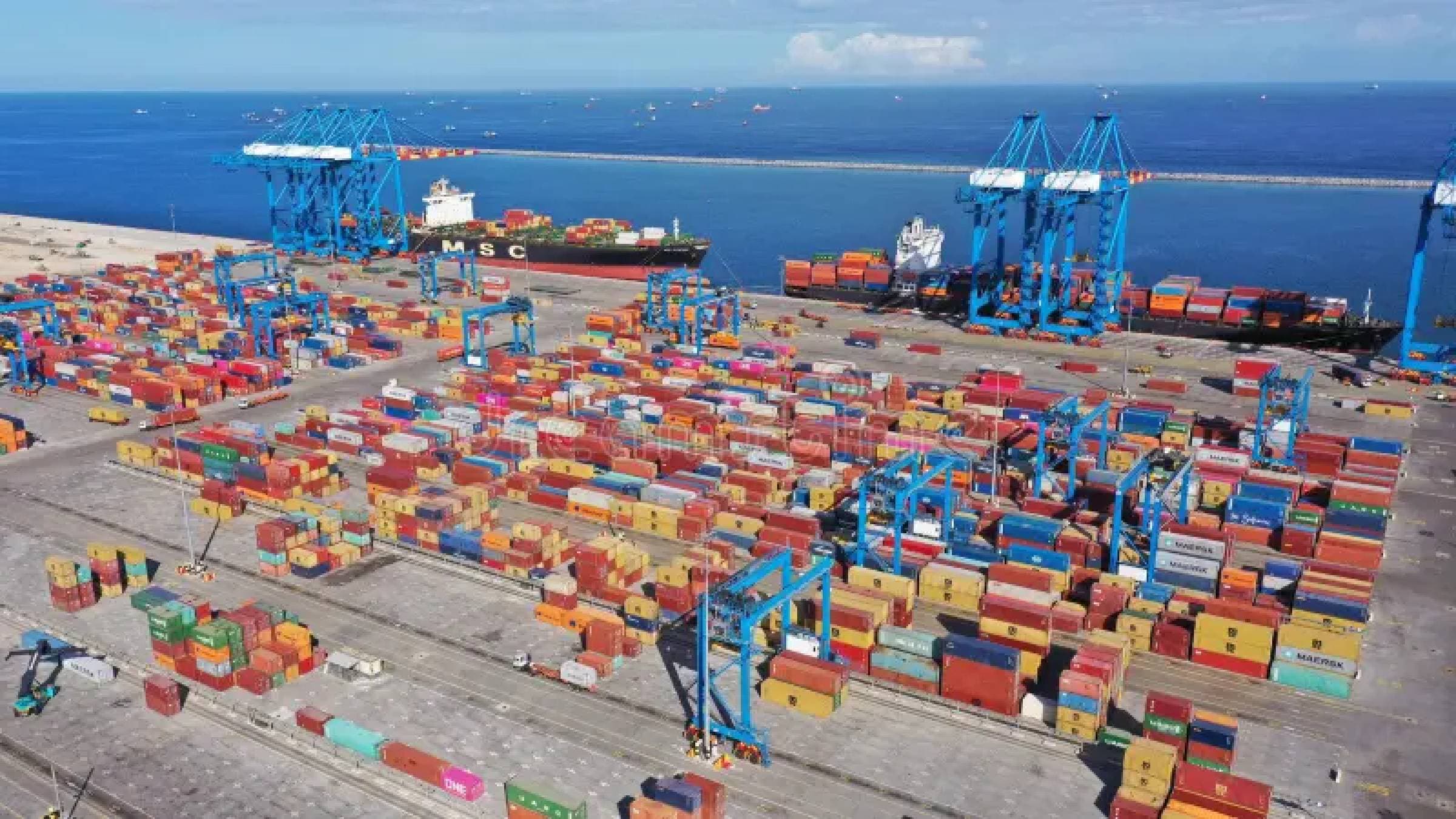 Aerial view of a container terminal with stacked cargo, gantry cranes and ships alongside the berth